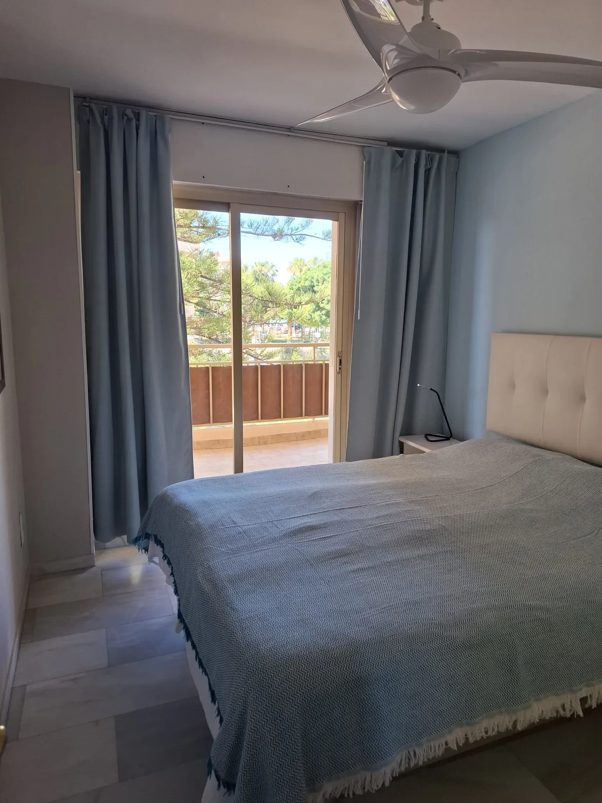 Slaapkamer met tweepersoonsbed, plafondventilator en toegang tot het balkon